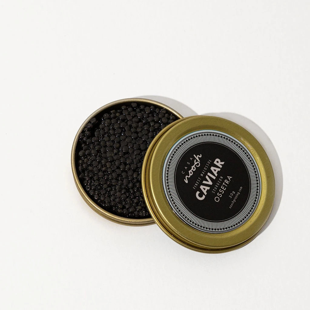 Open container of caviar with a gold lid on a white background